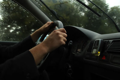 Hand holding steering wheel while driving in the rain. journey on the road with speed in a rainy day