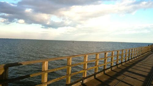 Pier on sea against cloudy sky