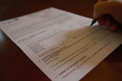 Cropped hand of person writing on filling form at table