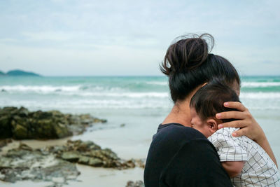 Woman looking at sea shore against sky