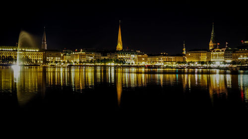 Historic buildings reflection in binnenalster against sky at night