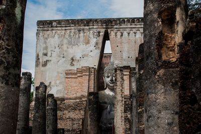 Buddha statue seen through weathered wall