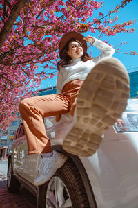 Portrait of young woman sitting on car