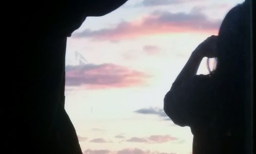 Close-up of silhouette hand against sky during sunset