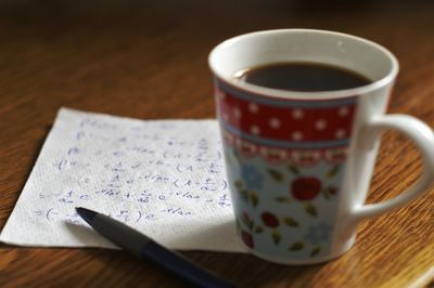 Close-up of mathematical formula on napkin with coffee on table