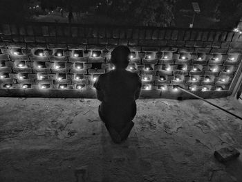 Rear view of woman standing against illuminated lights