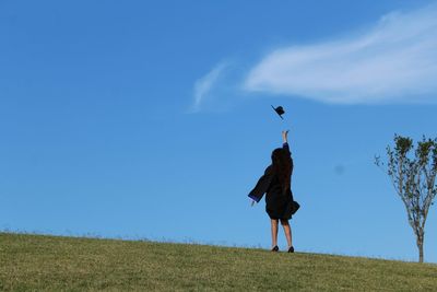 Woman standing on field against blue sky