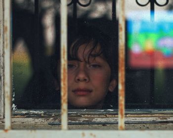 Portrait of boy looking through window in building