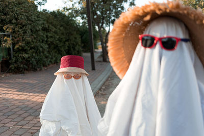 Trendy sheet ghosts costumes on little kids standing on a suburbs street. happy halloween holiday