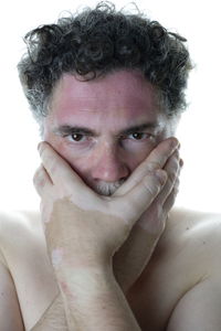 Close-up portrait of shirtless young man against white background