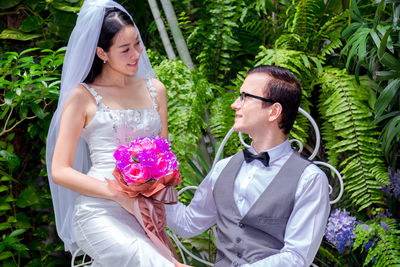 Married couple holding bouquet sitting outdoors