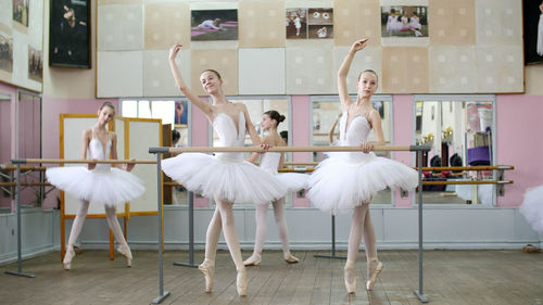 In the ballet hall, girls in white ballet tutus, packs are engaged at ballet rehearse croise forward