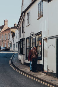 Rear view of man walking on street amidst buildings