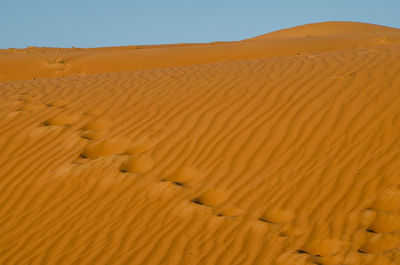 Sand dunes in desert against clear sky