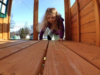 Girl climbing on wooden play equipment at playground