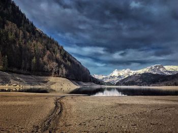 Scenic view of lake by snowcapped mountains against sky