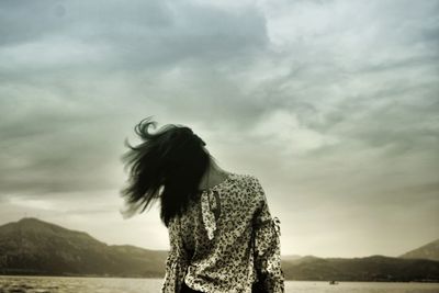 Woman standing at shore against sky