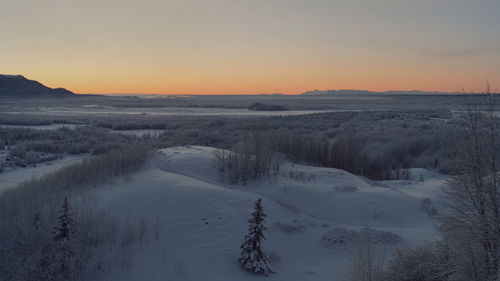 Scenic view of snow covered landscape against sky during sunset