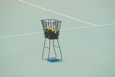 Tennis balls in basket on court during sunny day