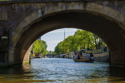 People on boat sailing in river against sky