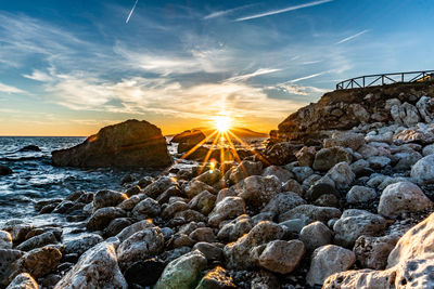 Rocks on shore against sky during sunset