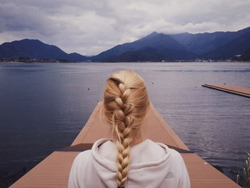 Rear view of braided woman on pier at lake 