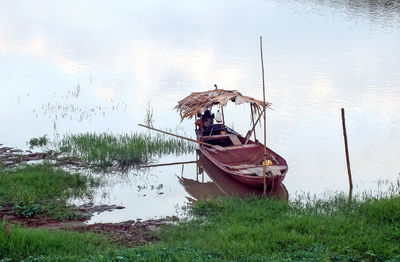 Boat moored at lakeshore against sky