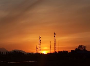 Silhouette of communications tower against sky during sunset