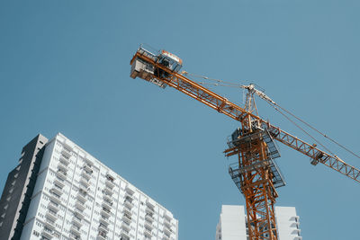 Low angle view of tower crane against blue sky