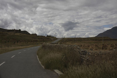 Road amidst field against sky