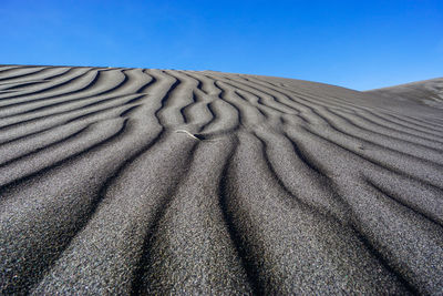 Surface level of sand dune against blue sky