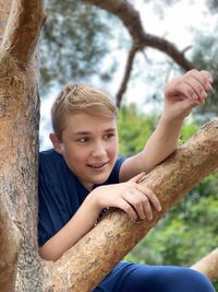 Portrait of boy smiling by tree trunk