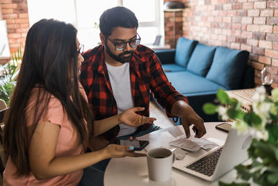 Young woman using laptop while sitting on sofa at home