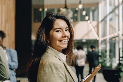 Side view portrait of smiling businesswoman with long hair at convention center