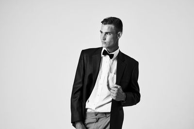 Portrait of young man looking away against white background