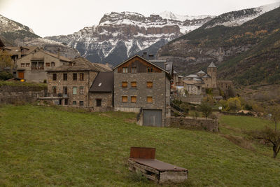 Houses on field by buildings against mountains