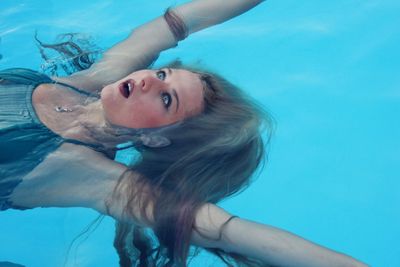 High angle view of young woman with mouth open swimming in pool