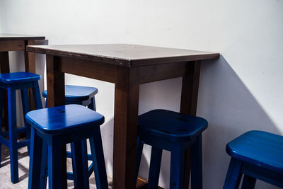 Empty chairs and table against wall