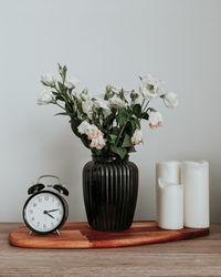 Flower vase on table against white wall