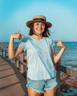 Portrait of smiling young woman standing against sea
