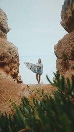 Portrait of young woman with surfboard standing at beach