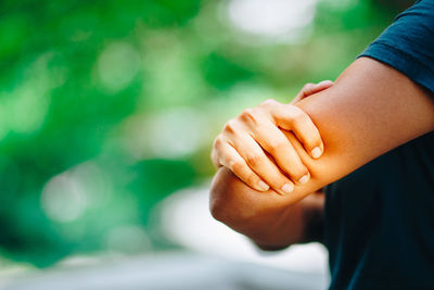 Close-up of woman with elbow pain while standing outdoors