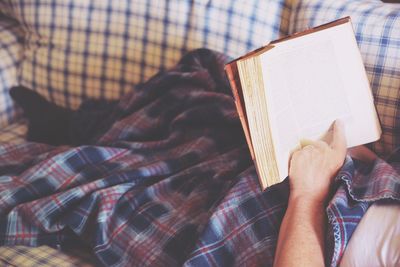 Low section of person resting book on sofa