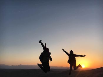 Silhouette of people playing at sunset