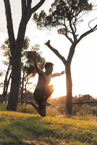 Man slacklining on tightrope during sunset