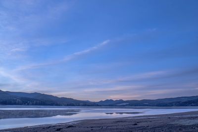 Scenic view of lake against blue sky during winter