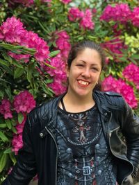 Portrait of smiling young woman standing by flowering plants