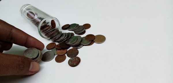 Close-up of hand holding coins over white background