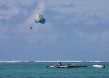 Person paragliding over sea against sky