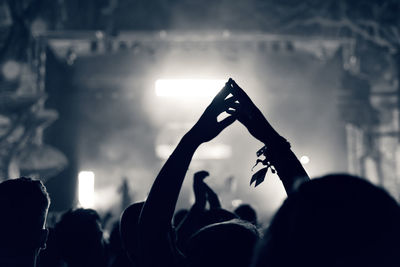Silhouette people at music concert against sky at night